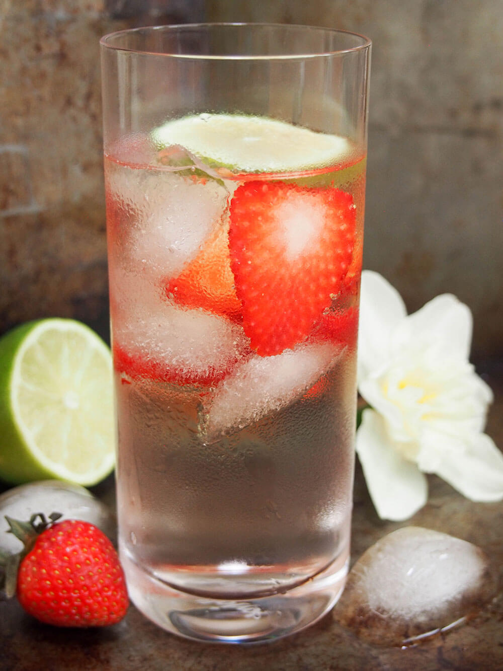  glass of strawberry St Germain gin and tonic from side showing strawberries in glass