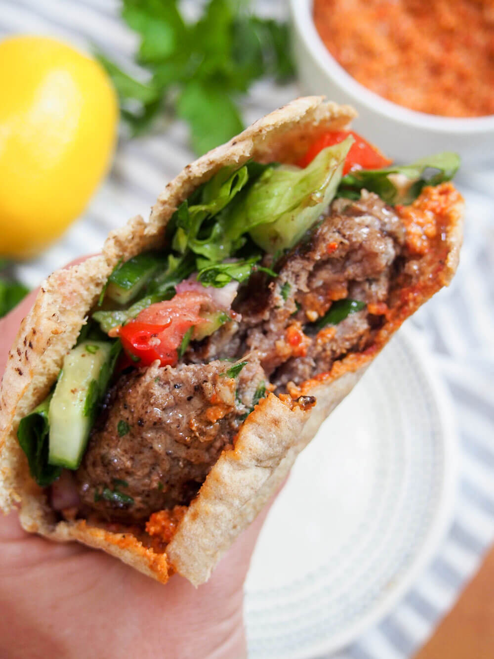 lamb kofte burger held in hand with bite taken