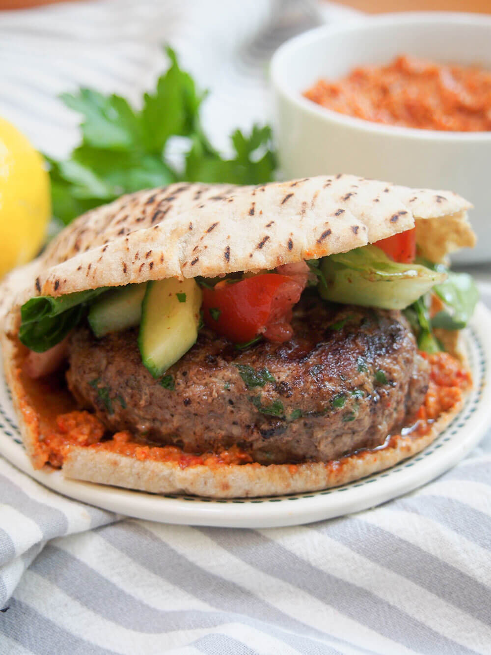 lamb kofte burger viewed from side with salad on top of burger inside pita