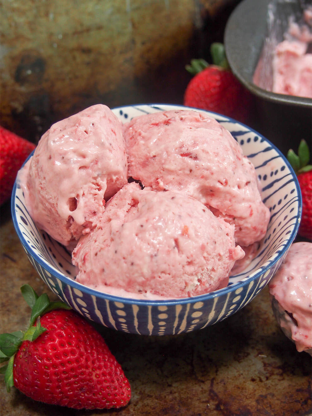 no churn roasted strawberry ice cream in bowl with strawberries to side