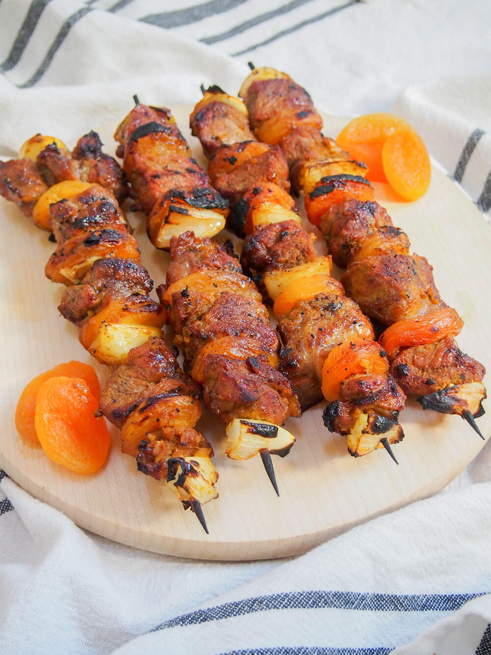 Four skewers on chopping board with apricots to side