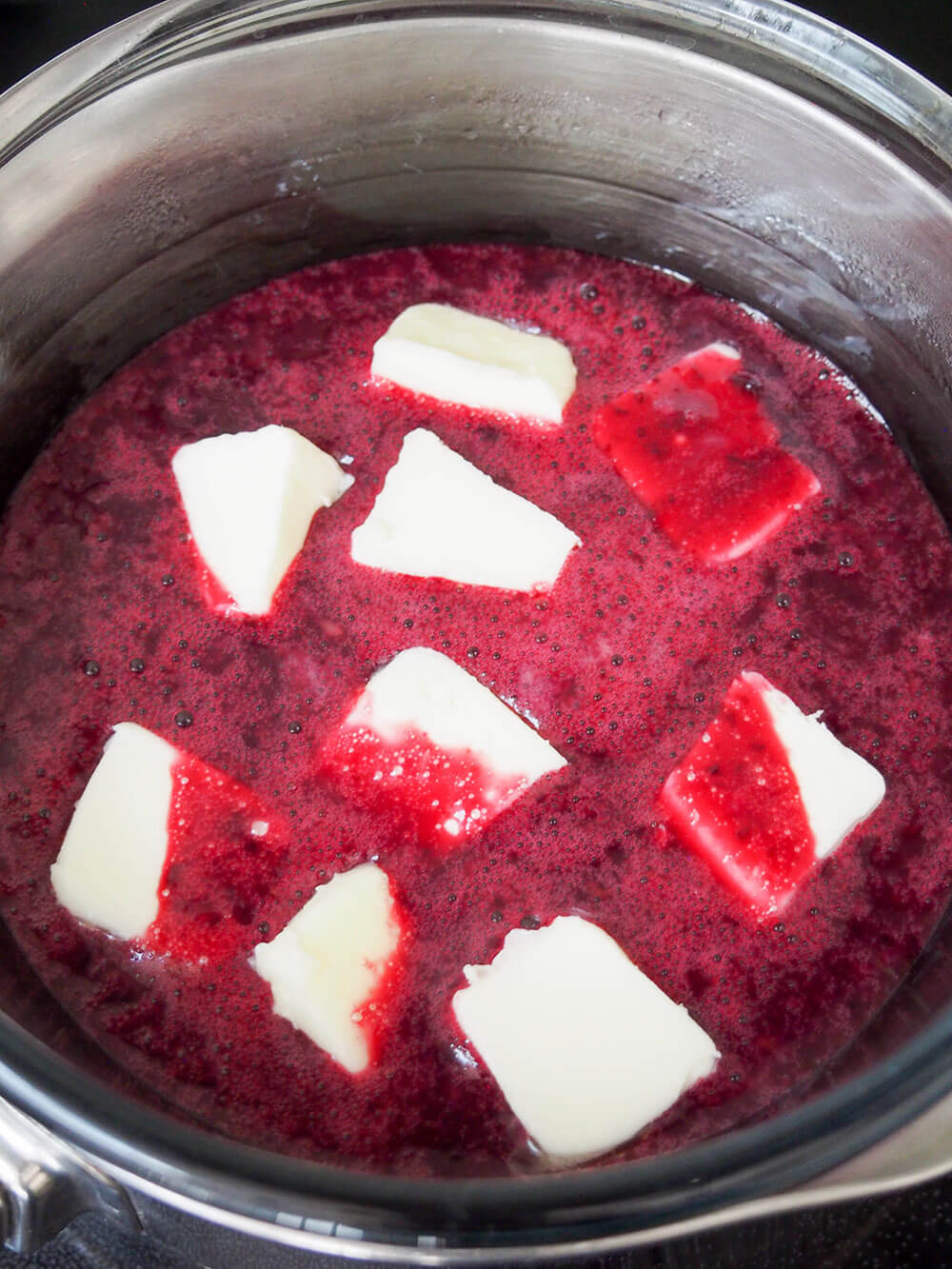 adding butter chunks to make blueberry curd