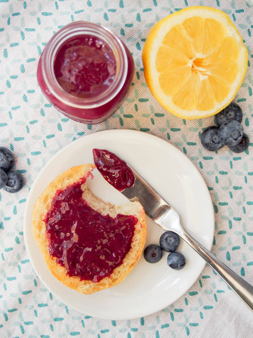 Blueberry curd in jar and on bread with bite taken from it