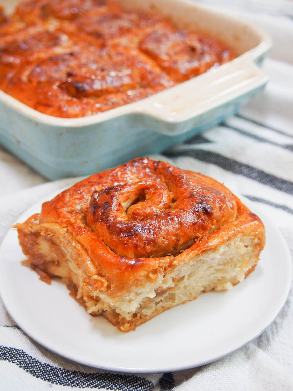 golfeado sticky bun sitting on plate in front of baking dish with rest