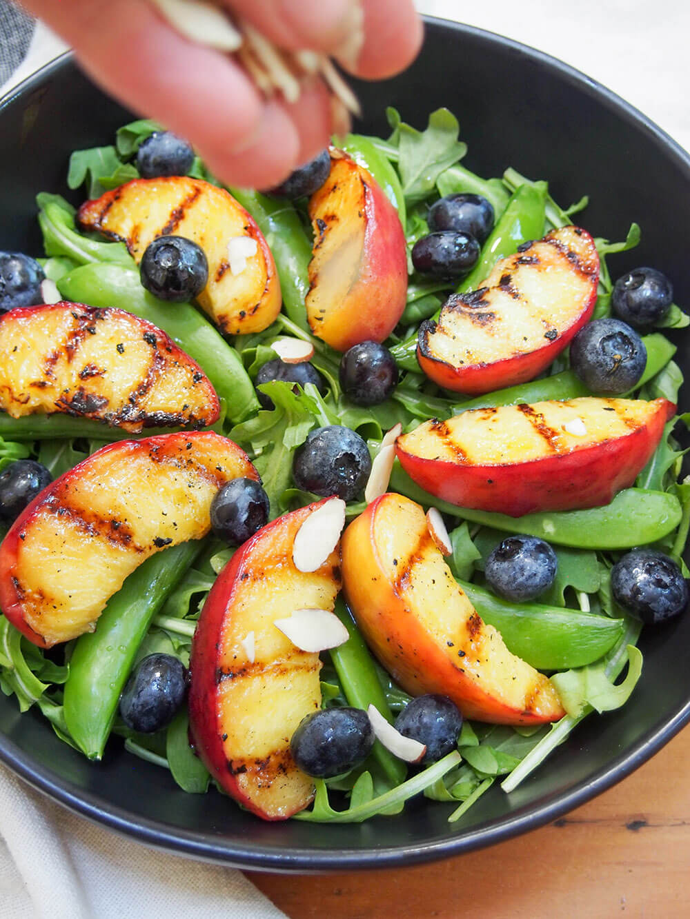 sprinkling almonds on top of salad
