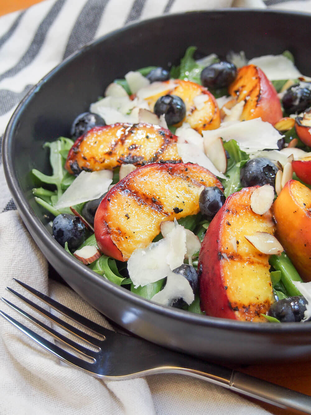 grilled peach salad from side with fork in front of dish