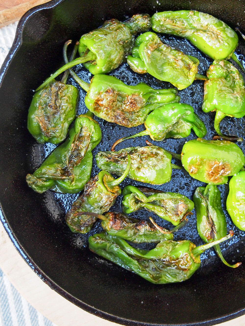 blistered Padron peppers in skillet from overhead