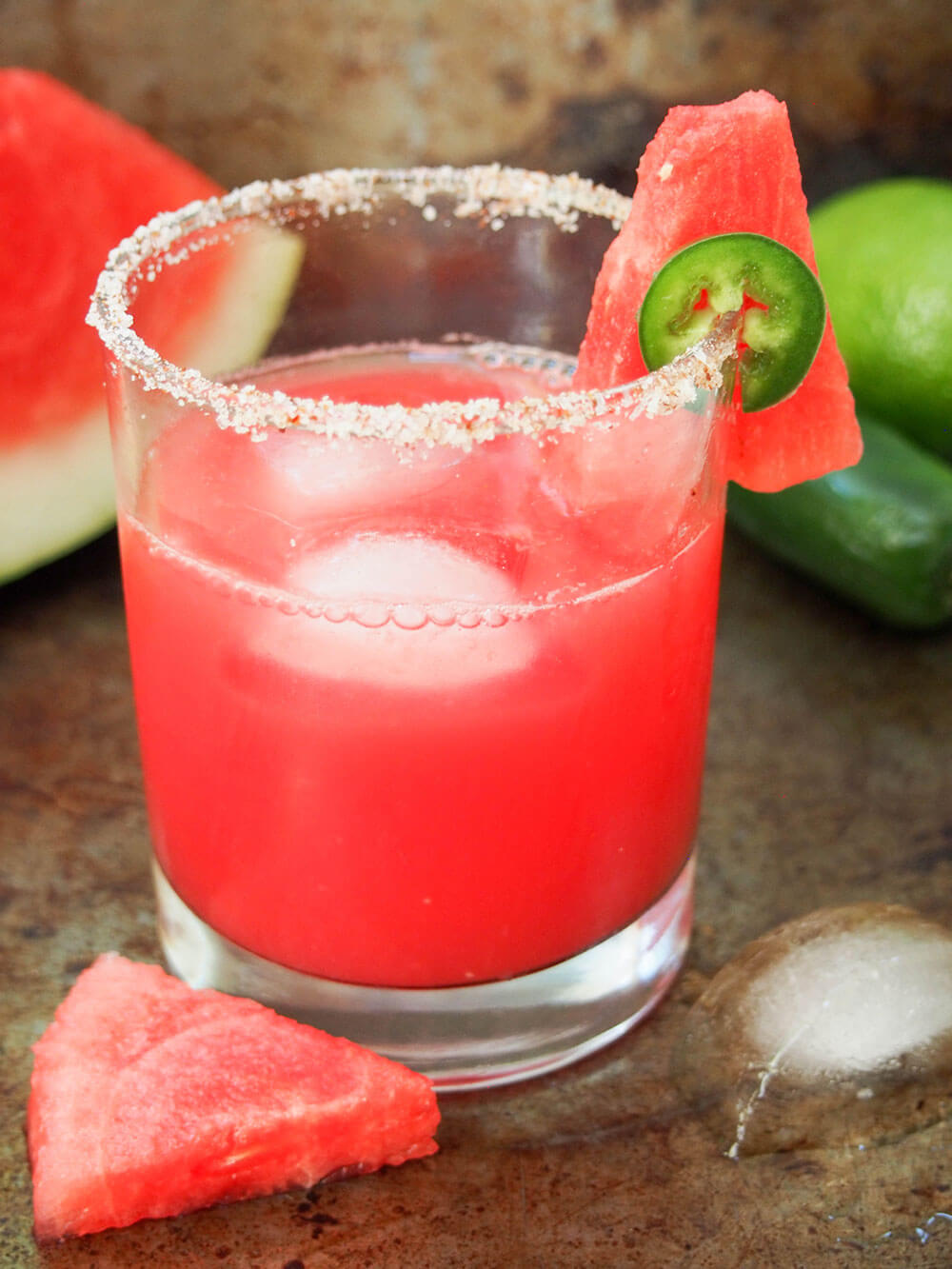 glass of spicy watermelon margarita with chunk of watermelon in front of glass