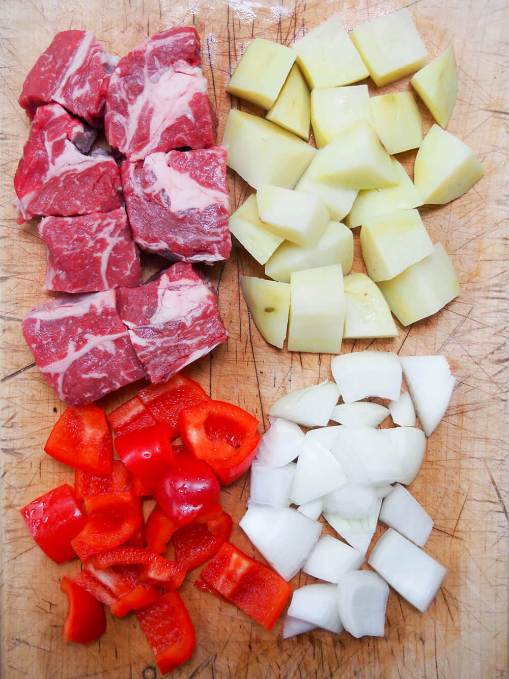 diced steak, potatoes, pepper and onion laid out on chopping board