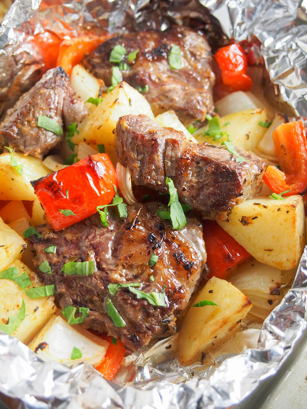 Steak foil packet with potato, pepper and onion and garnished with parsley