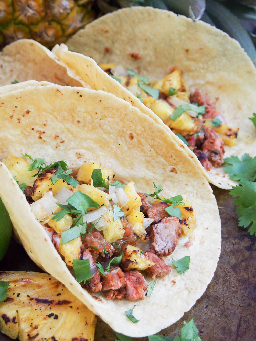 tacos al pastor side by side with slice of grilled pineapple to side