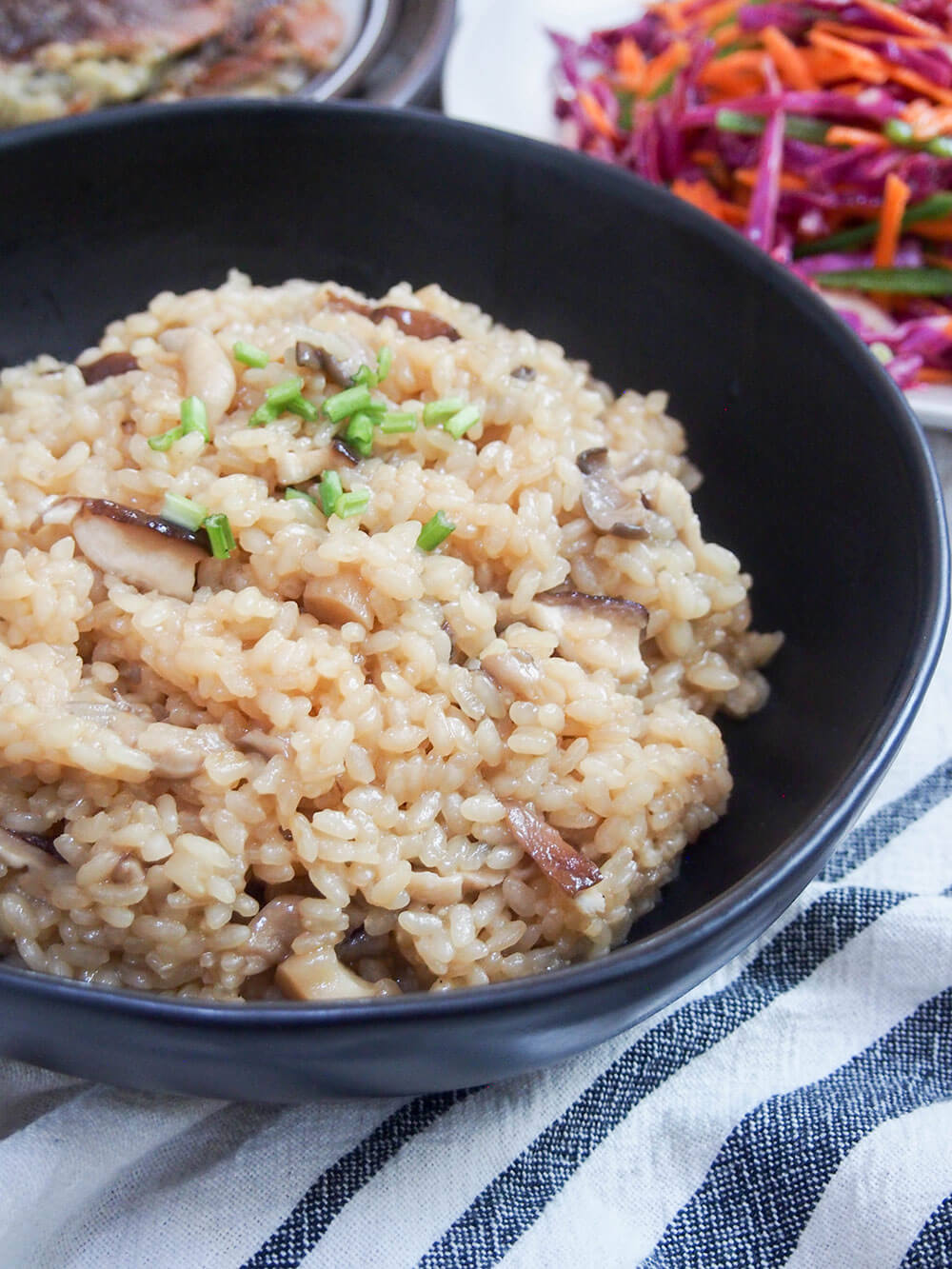 bowl of Japanese mushroom, rice kinoko gohan, with other dishes behind