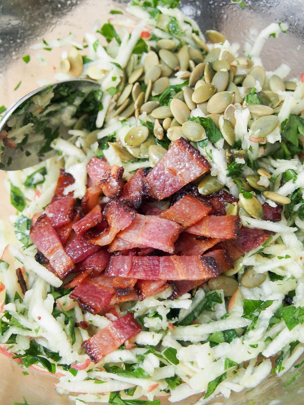 adding bacon and pepitas while making apple celeriac salad adding bacon and pepitas to apple celeriac salad