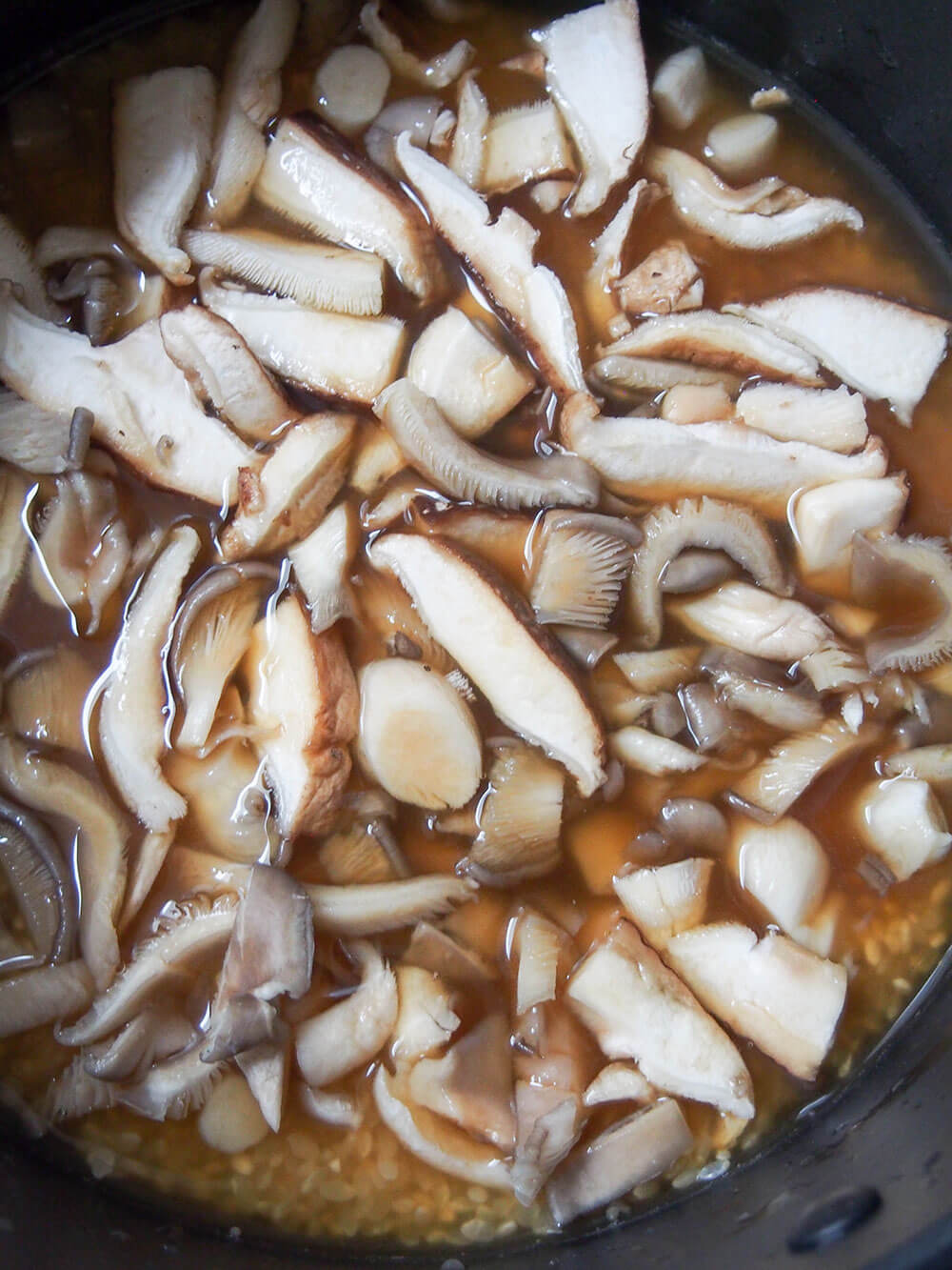 mushrooms on top of rice with water and seasonings during cooking