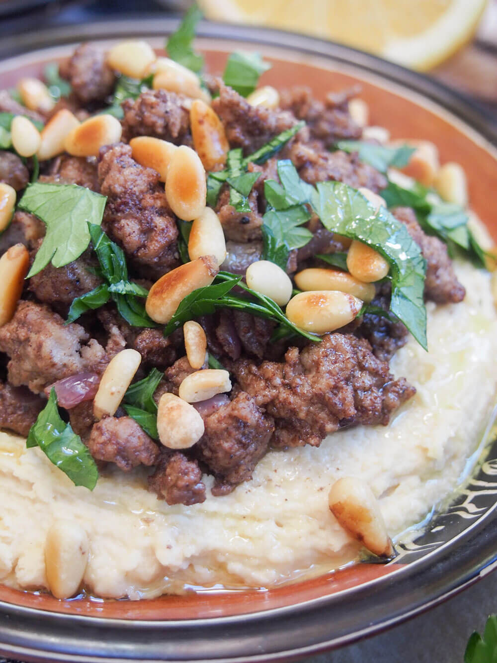 close up of Hummus kawarma (hummus with lamb) topped with pine nuts and parsley
