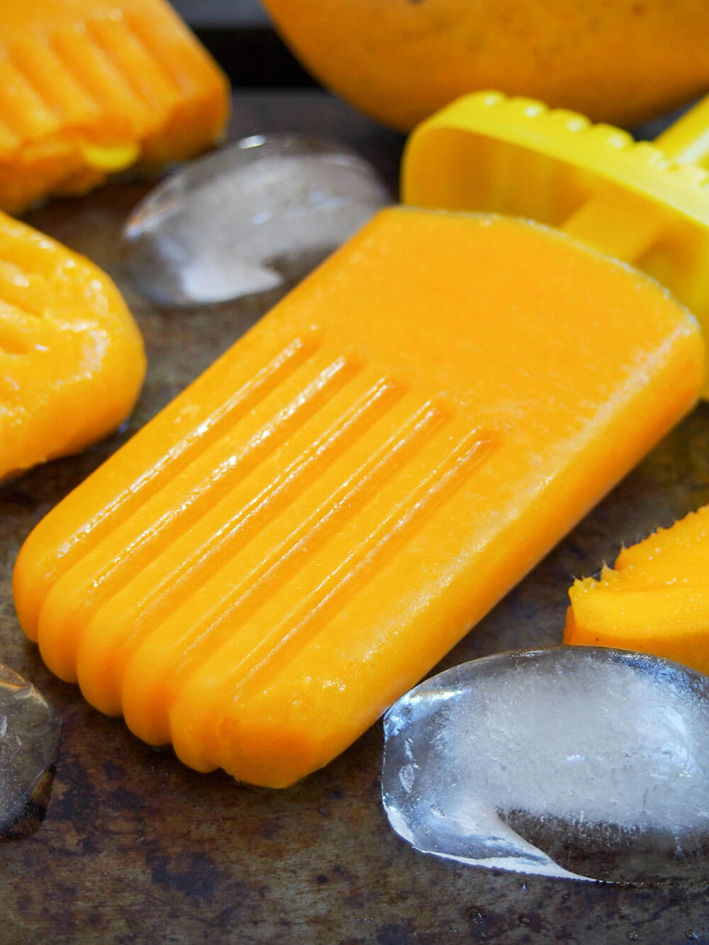 mango palatas (ice pops) on baking sheet with ice cubes around as decoration