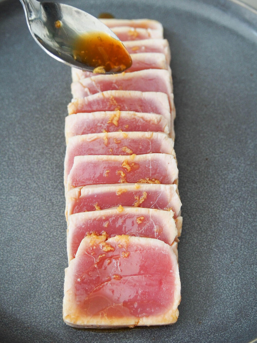 drizzling sauce over tuna slices