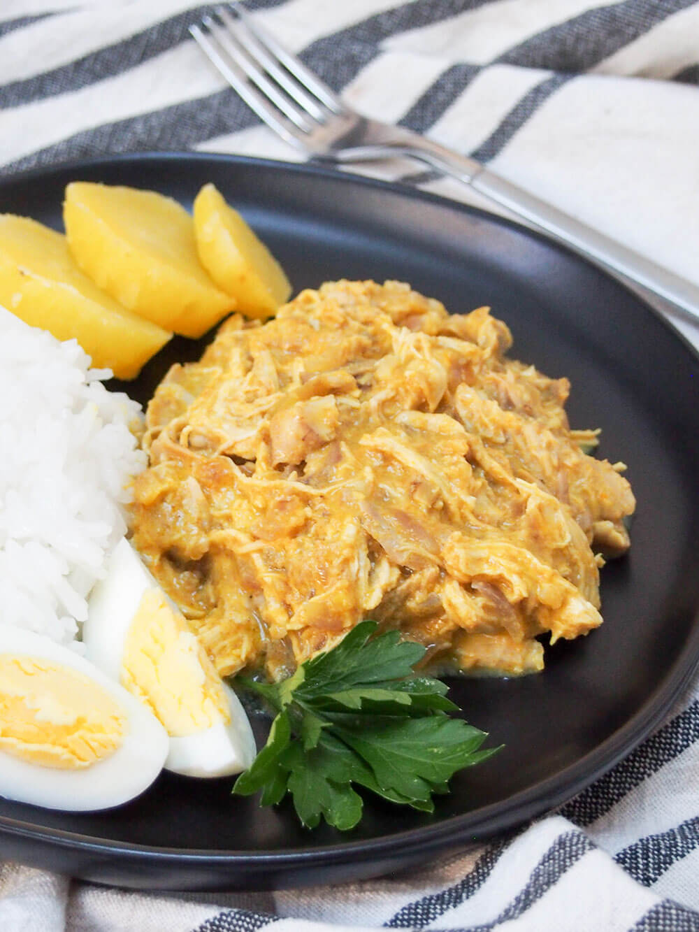 Aji de gallina is a classic Peruvian dish, with shredded chicken wrapped in a smooth, creamy sauce with chili, cheese and walnuts. It's a delicious meal, plus perfect to adapt for leftovers (both chicken and turkey). It's also great to make ahead. Aji de gallina (Peruvian chicken) served with traditional sides of rice, potato and egg with fork behind plate
