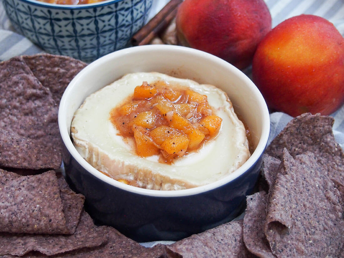 baked goat cheese with peach chutney in dish with chips around dish