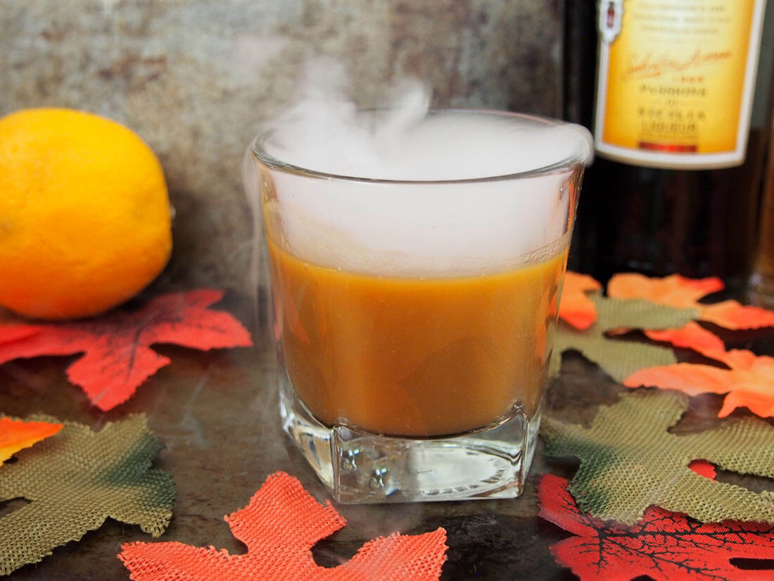 falling for orange: amaro pumpkin cocktail with bottle and orange behind
