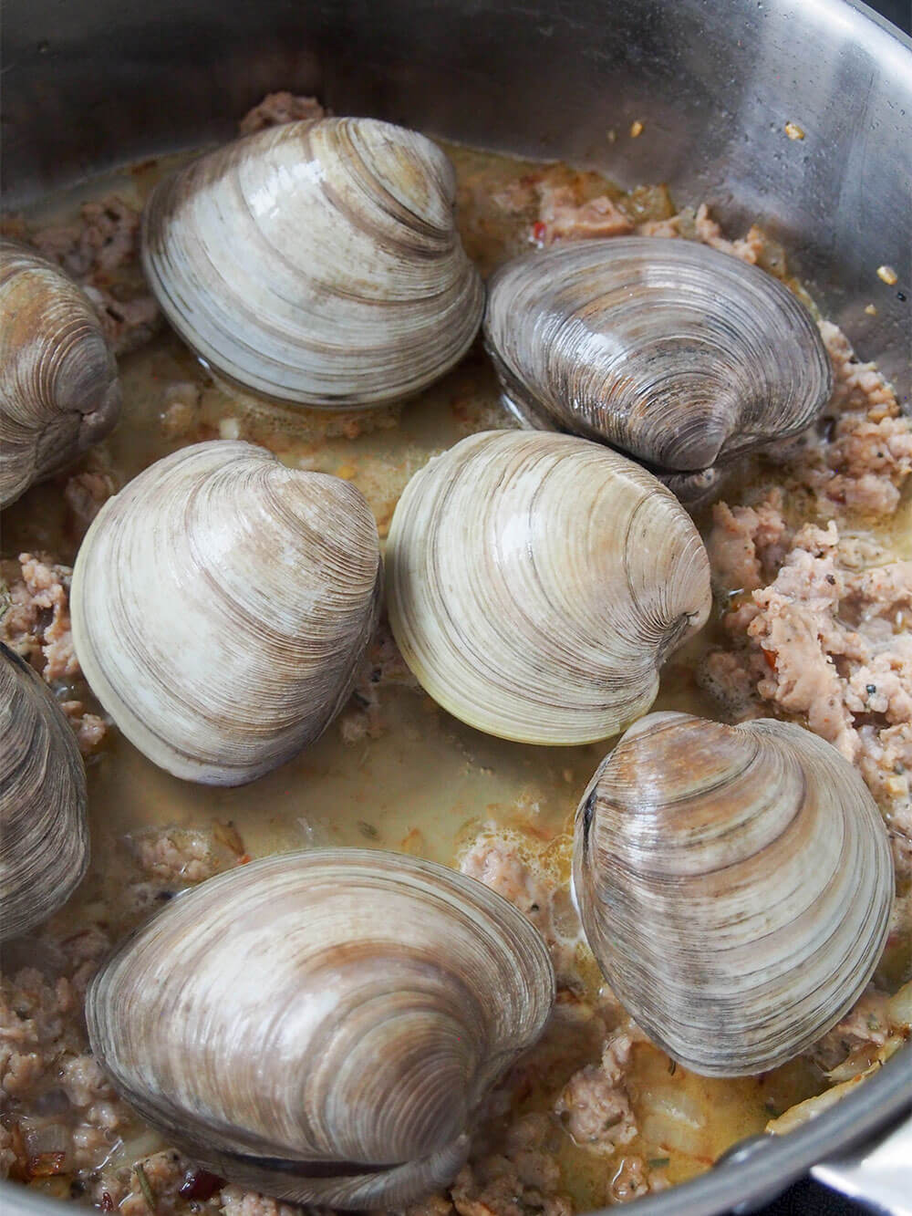 adding clams to sausage sauce base