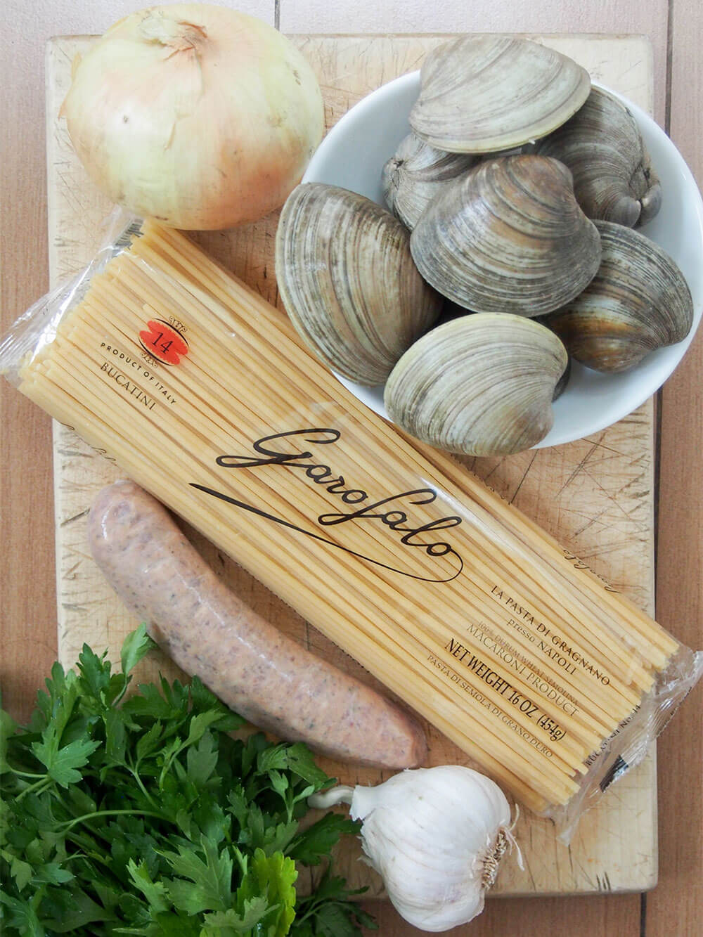 ingredients for Pasta with clams and sausage set on chopping board