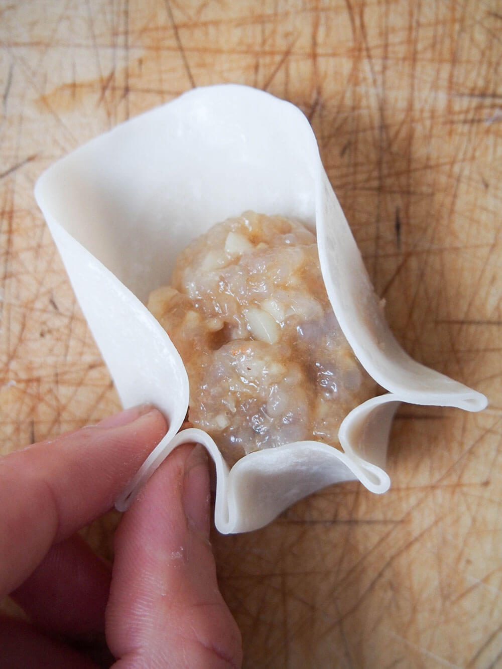 pinching edges of shrimp shumai to form pleats