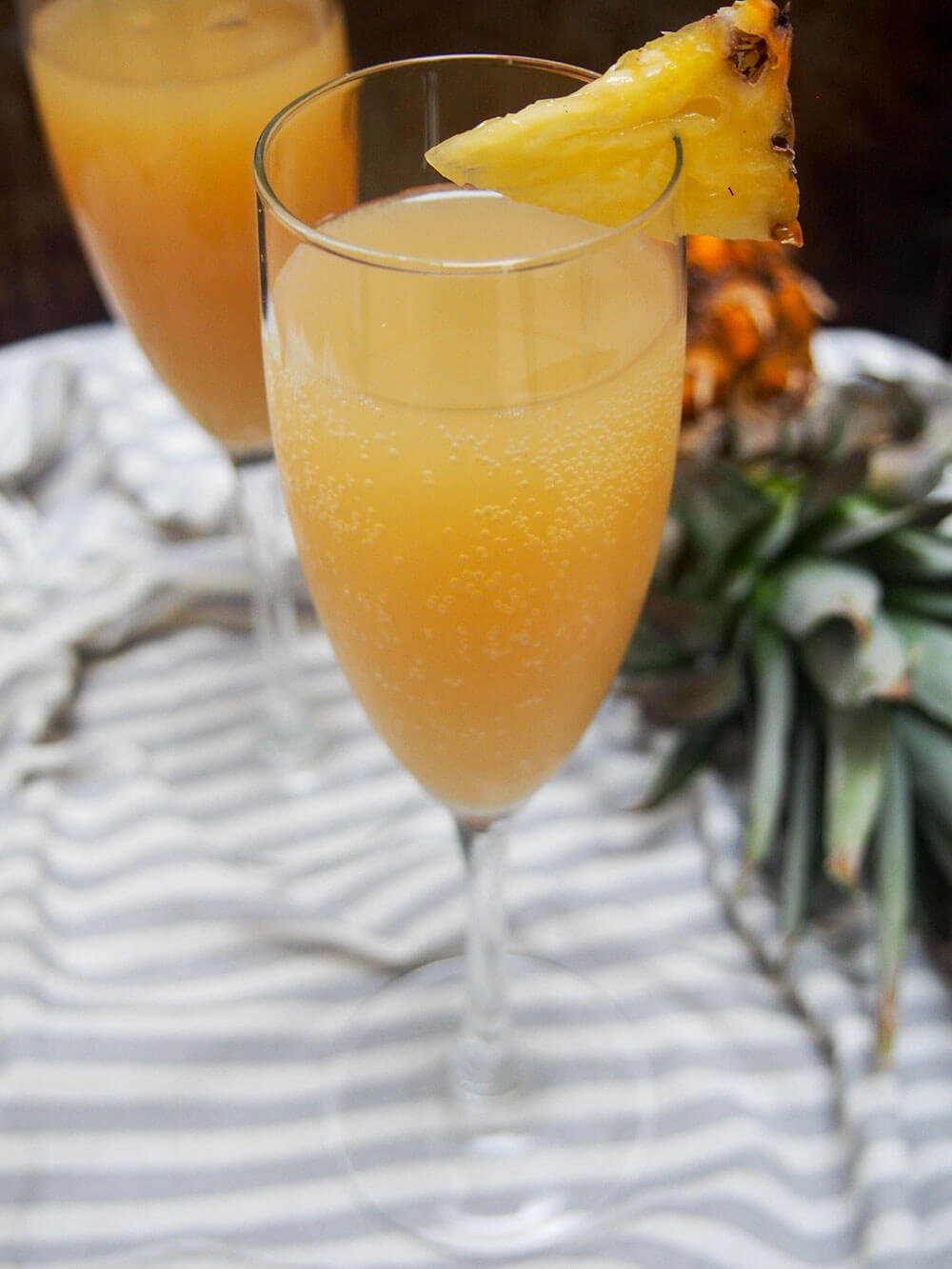 glass of pineapple mimosa garnished with a piece of pineapple