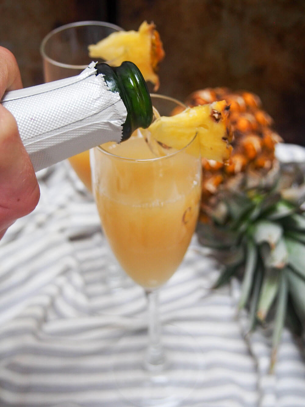adding champagne to base for pineapple mimosa