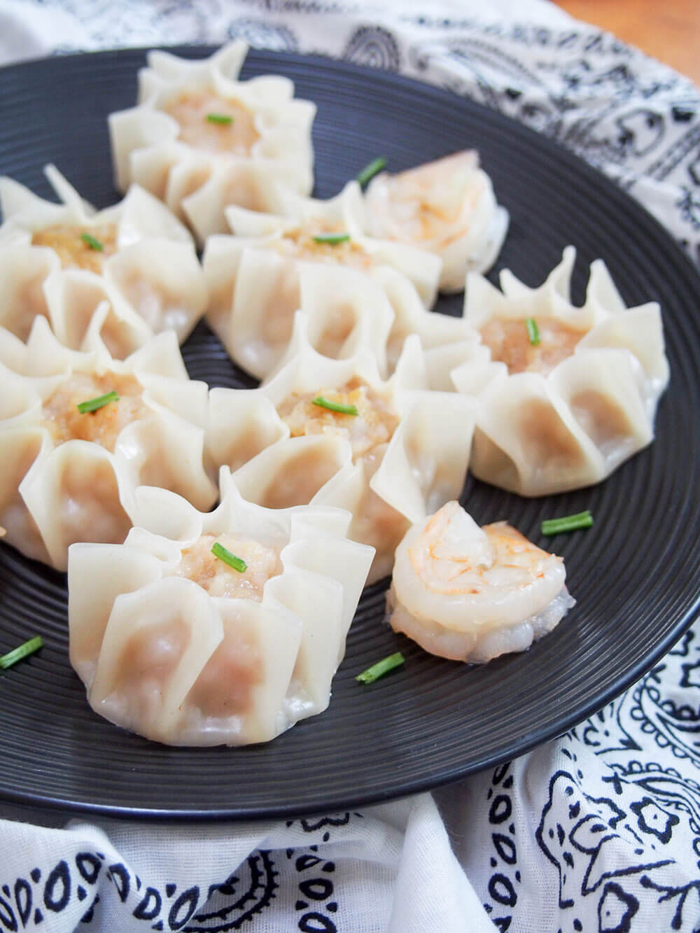 plate of shrimp shumai from side with chive garnishes