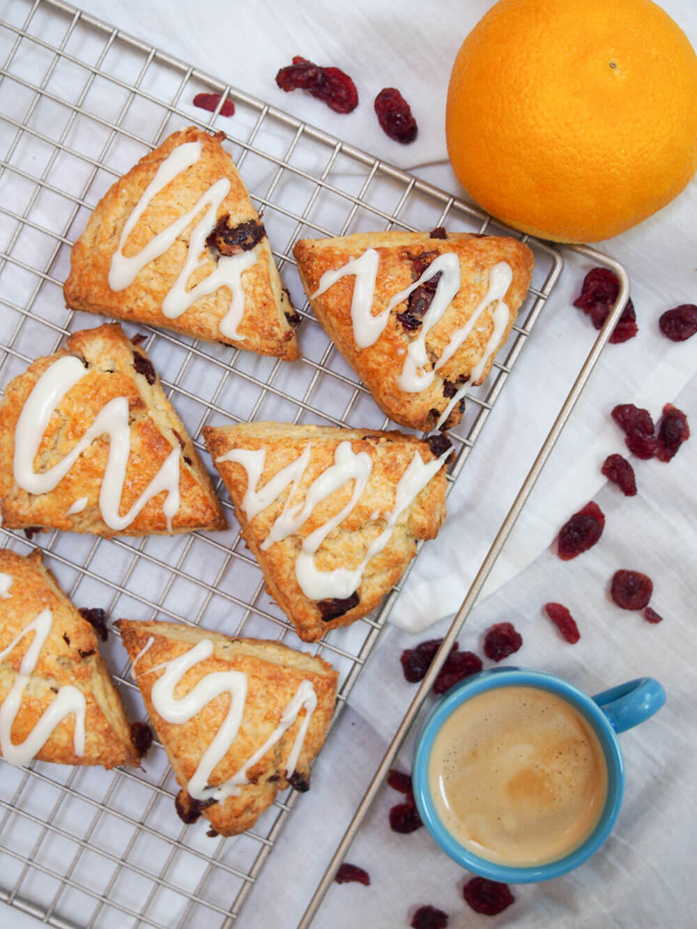 Cranberry orange scones on cooling rack with cup of coffee to side