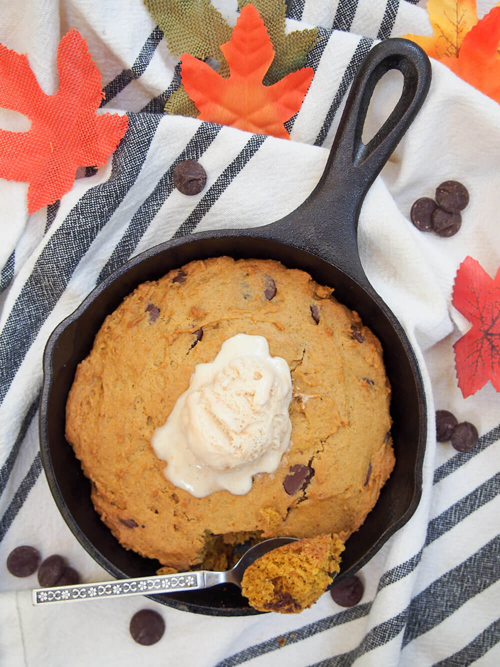 mini pumpkin skillet cookie from overhead with ice cream on top and some on spoon