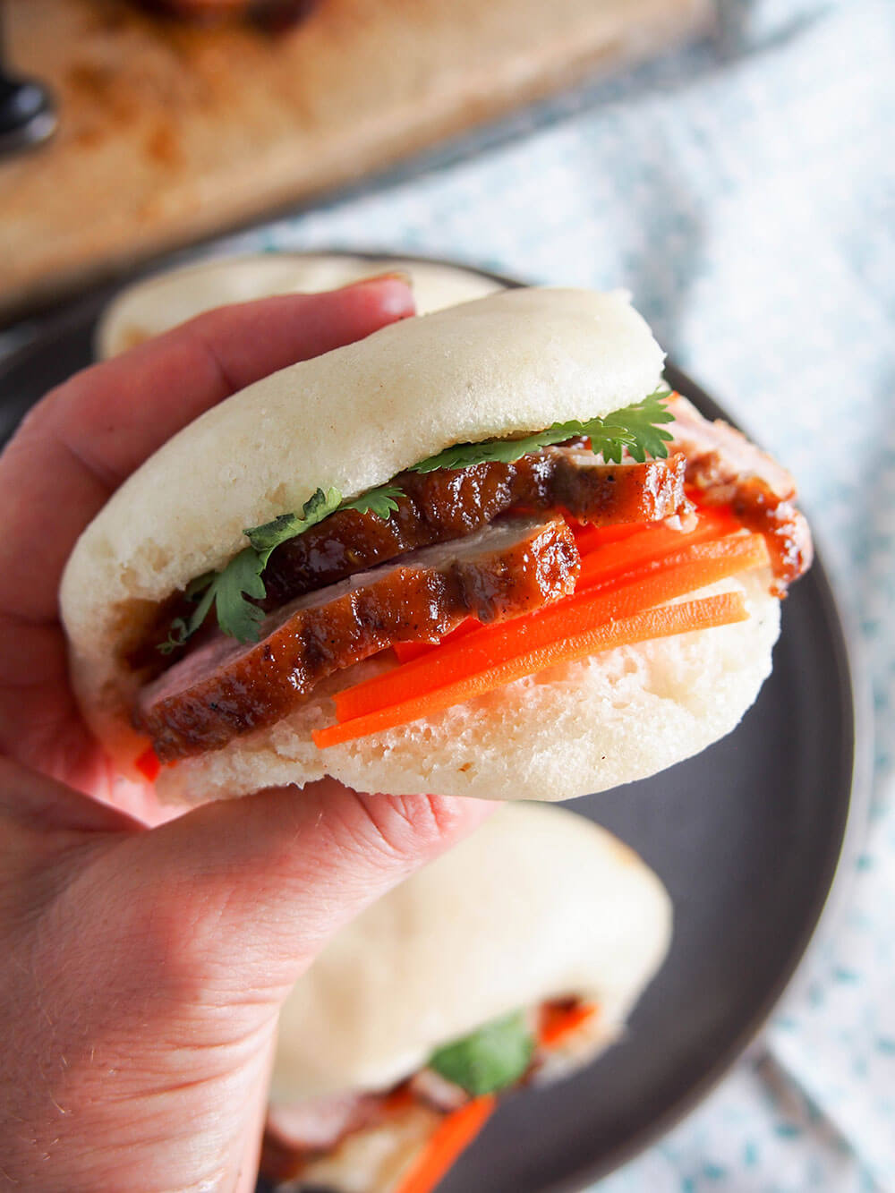 holding steamed bao bun with pork in hand