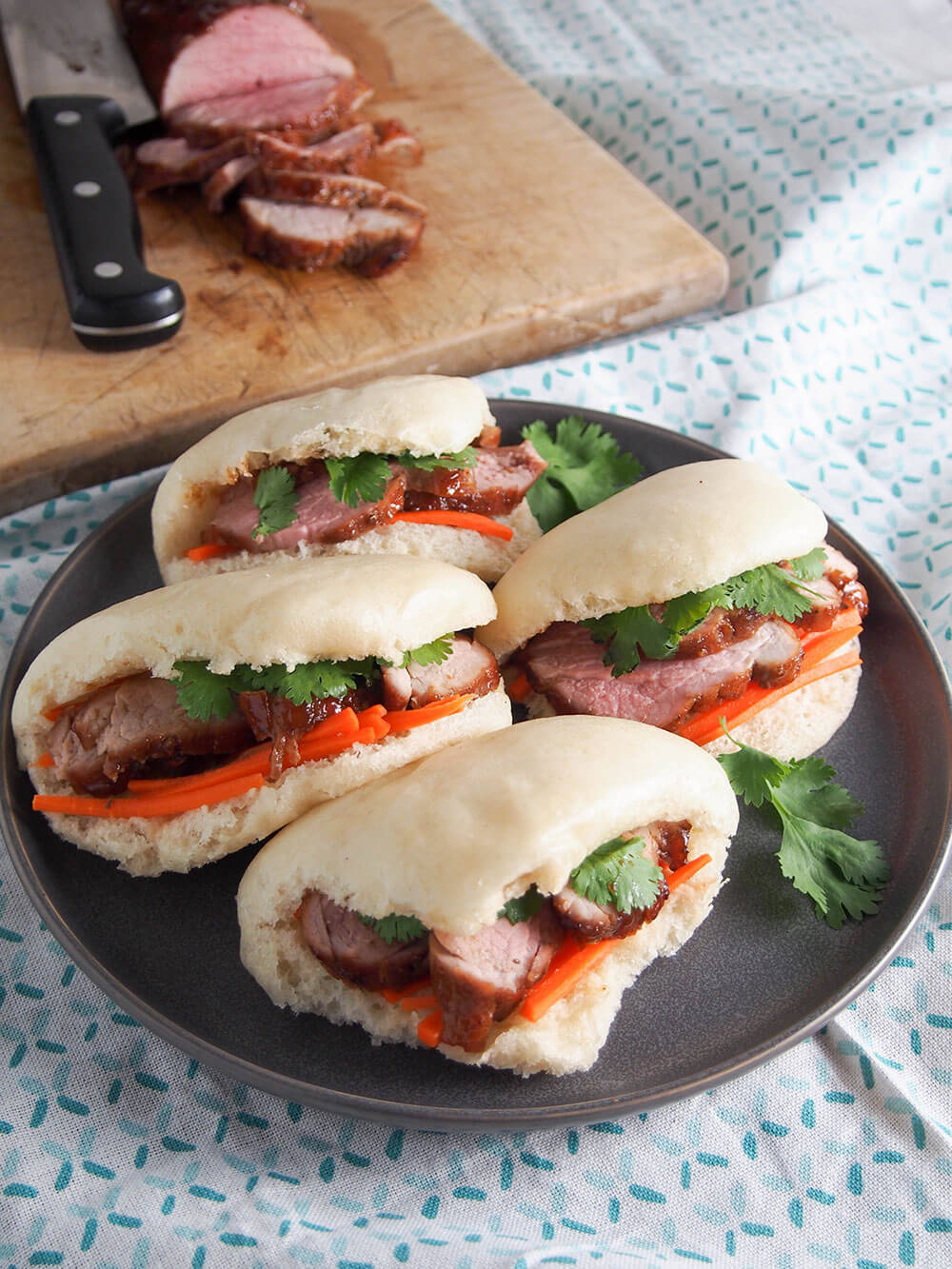 steamed bao buns with pork buns on plate with extra pork behind