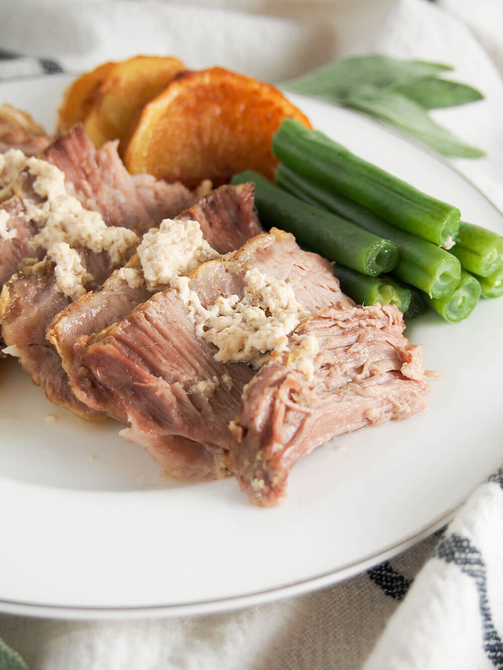 Milk-braised pork (maiale al latte) on plate with sides behind close up view