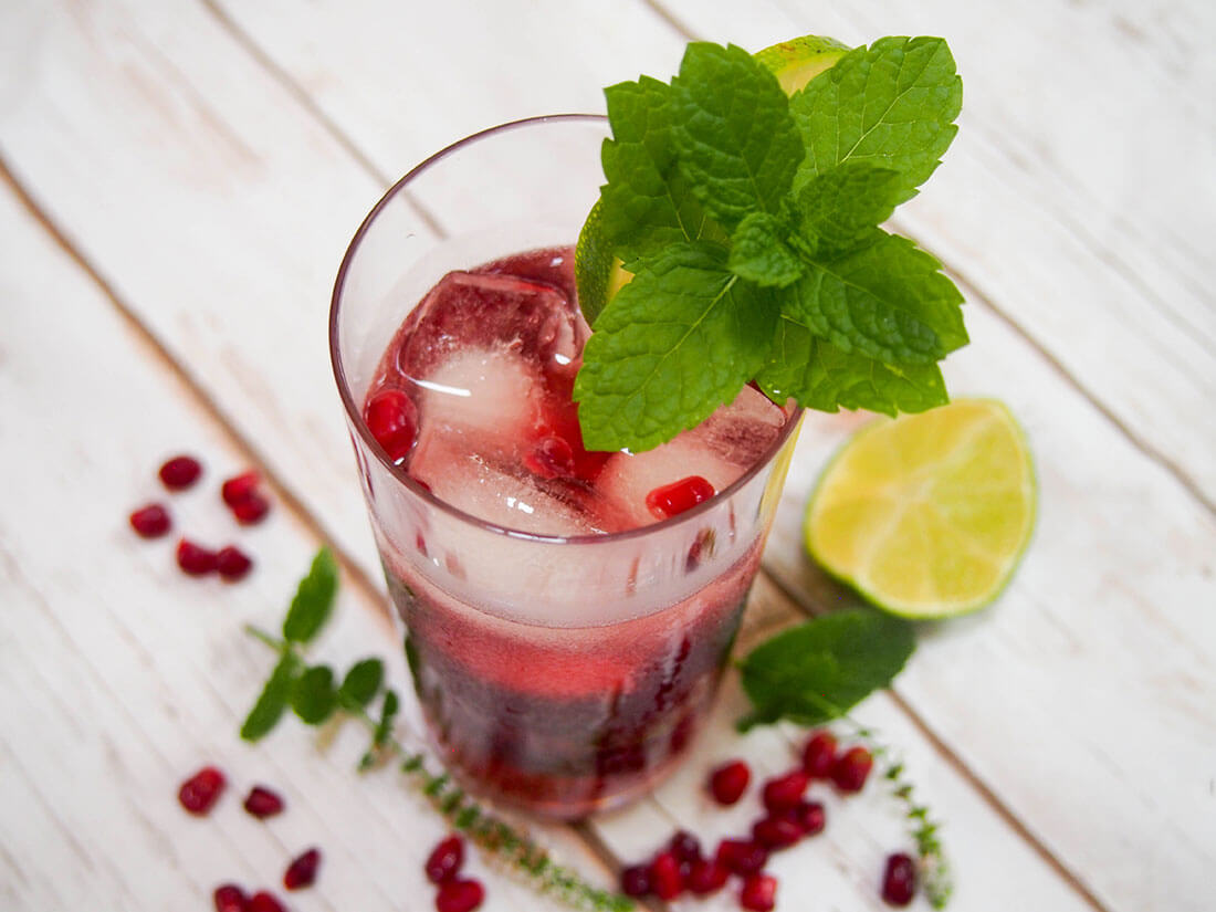 glass of pomegranate mojito with mint garnish on glass