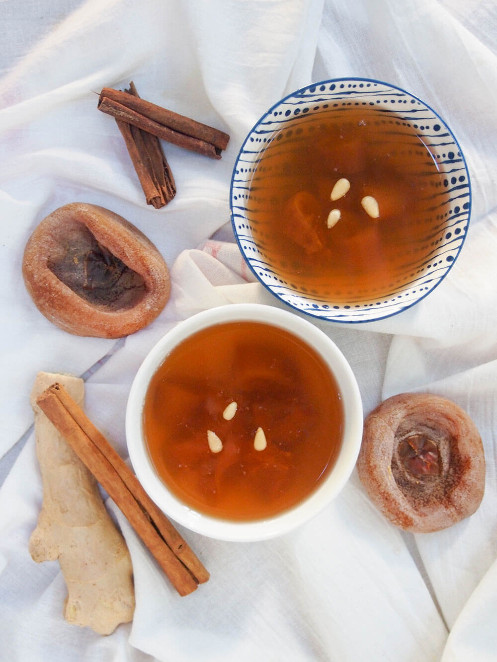 two bowls of Sujeonggwa (Korean cinnamon tea) with ingredients around bowls