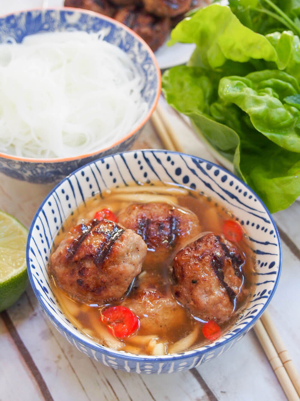 bowl of Bun cha Hanoi with sides - noodle and lettuce - behind