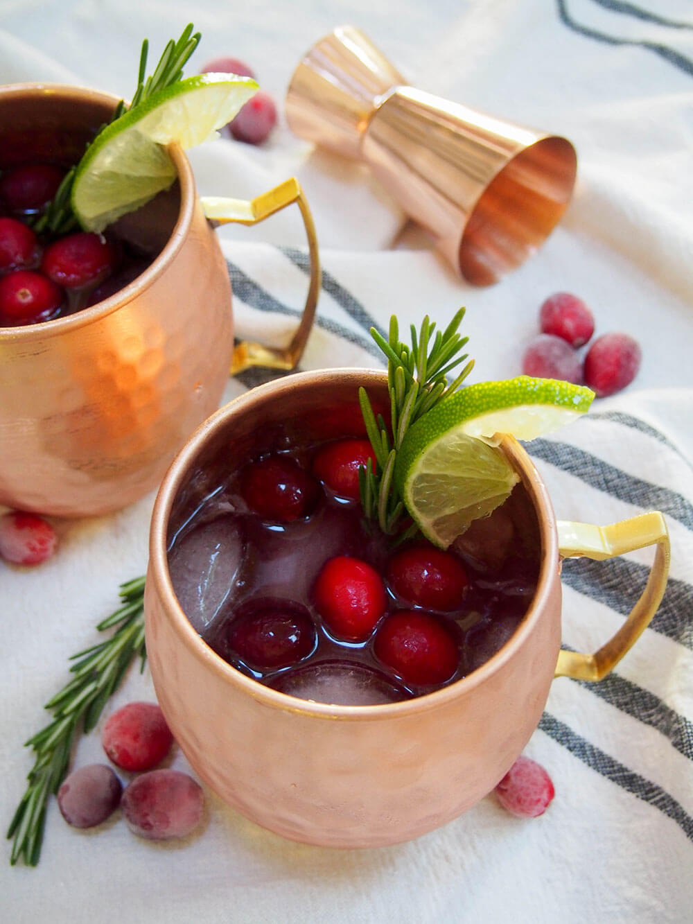 This cranberry Moscow mule is a simple seasonal twist on a classic cocktail, that can also easily be made as a mocktail. Perfect for a festive party! cranberry Moscow mule with cranberries, sprig of rosemary and slice of lime on top for decoration
