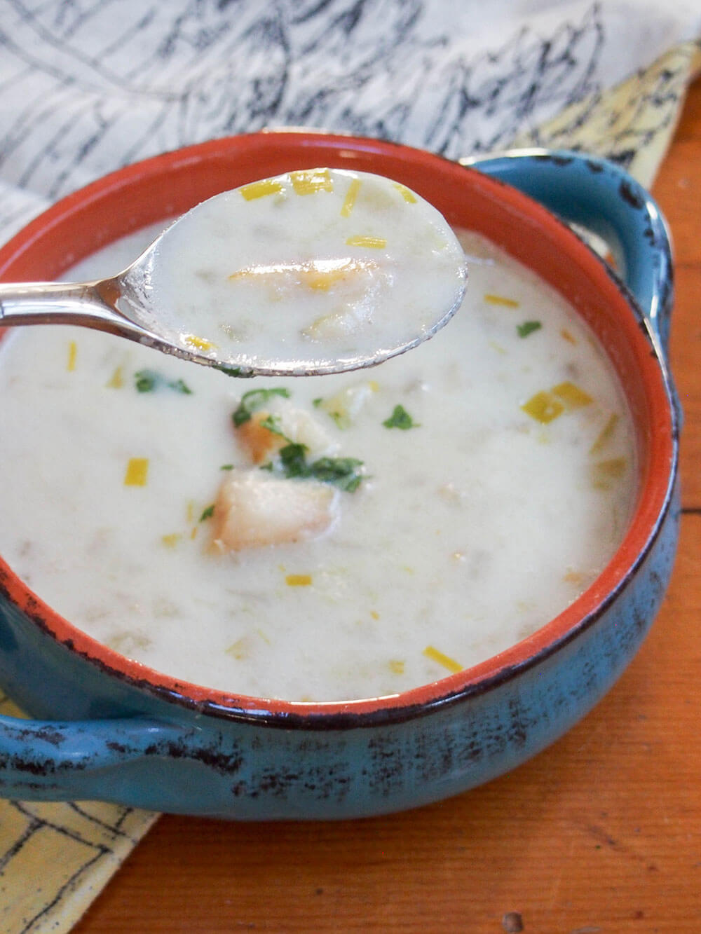 bowl of cullen skink chowder with spoon held above bowl