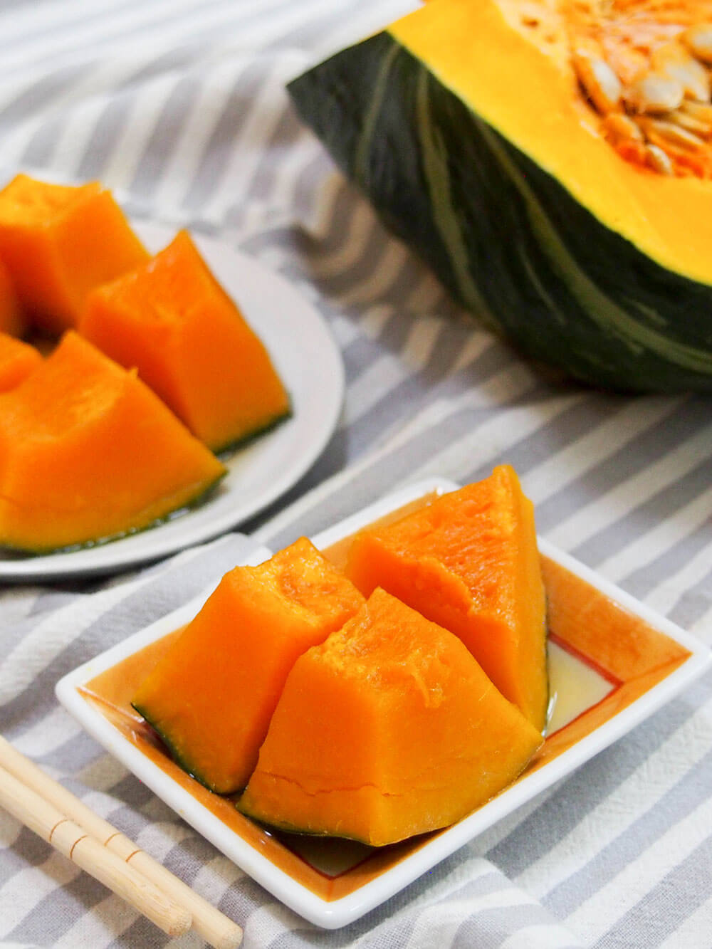 Kabocha no nimono (Japanese simmered squash) with piece of kabocha behind