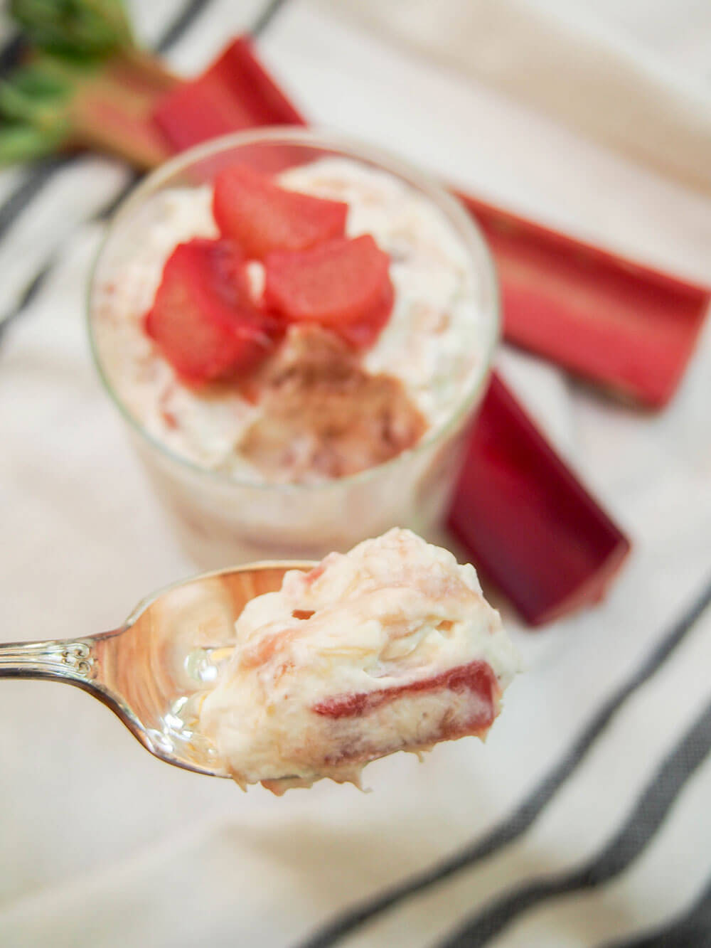 taking spoonful of rhubarb fool with glass with rest behind