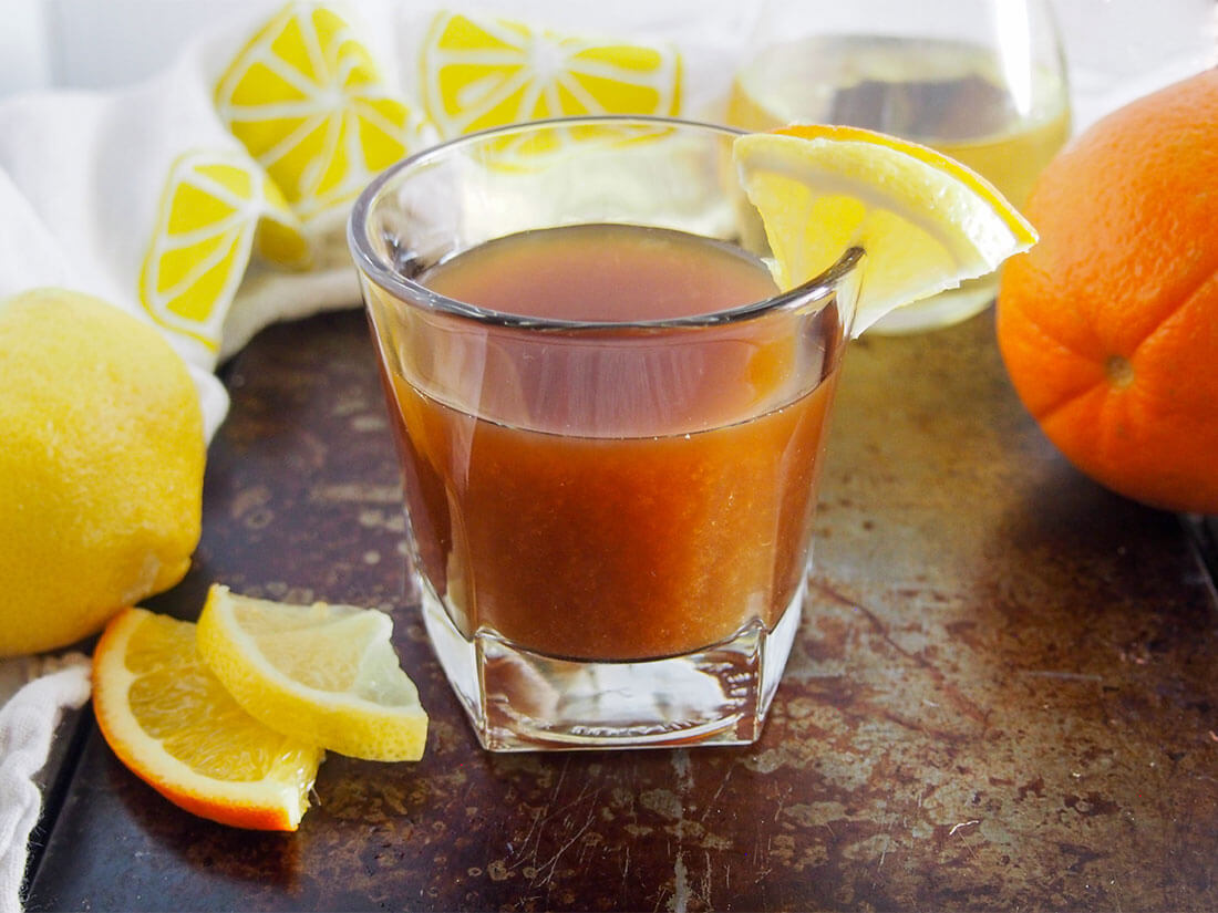 "Campfire in lemon groves" (amaro limoncello cocktail) in glass with slices of lemon and orange to side
