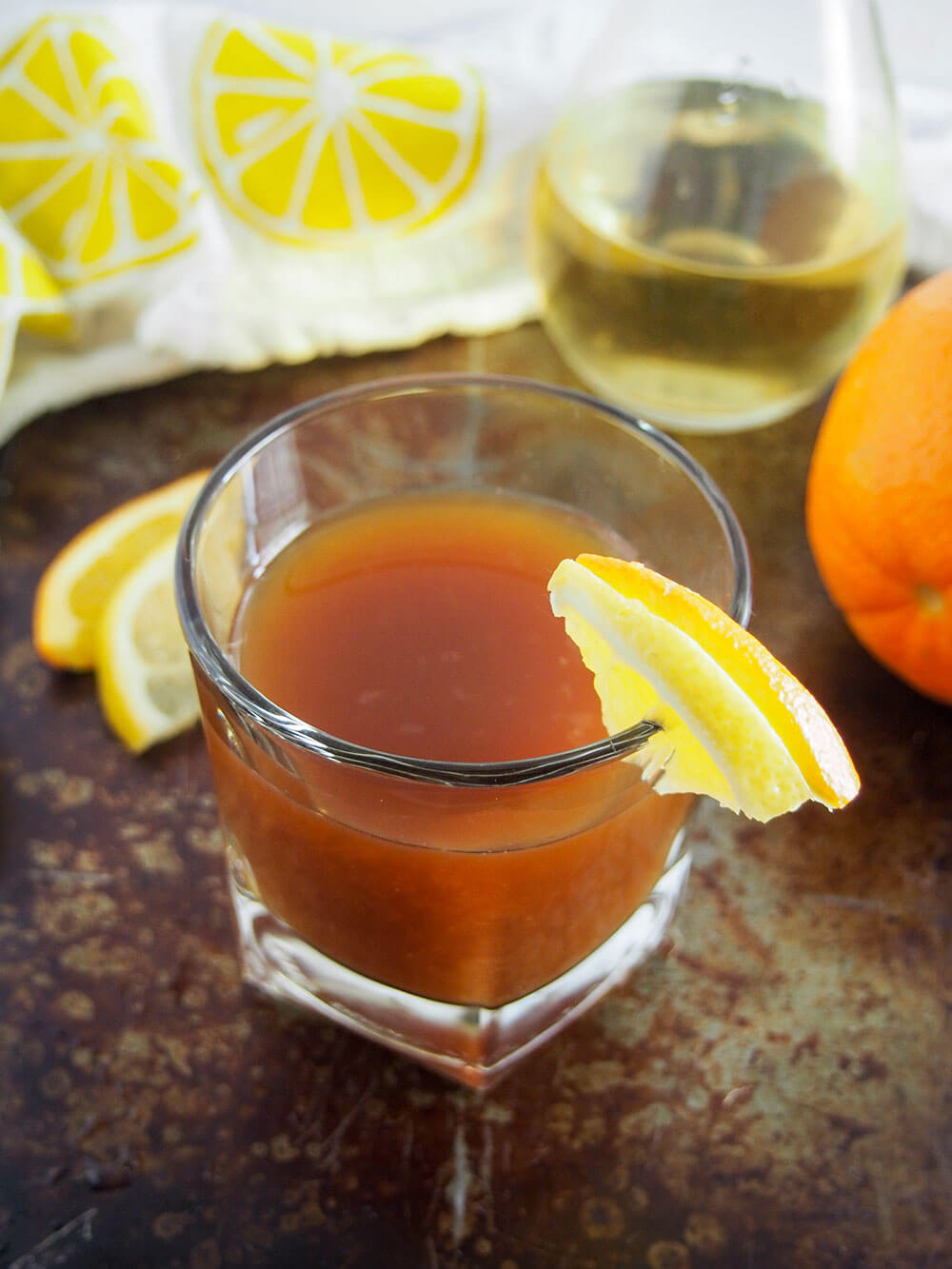 "Campfire in lemon groves" (amaro limoncello cocktail) with lemon orange garnish on glass