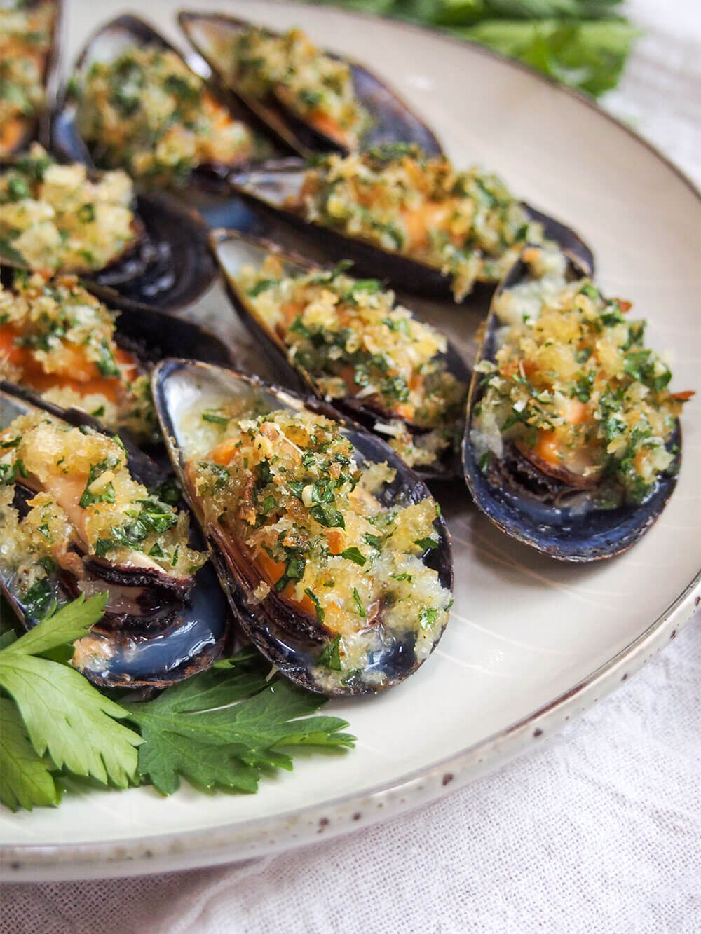 baked mussels close up showing crumbs and herbs on top