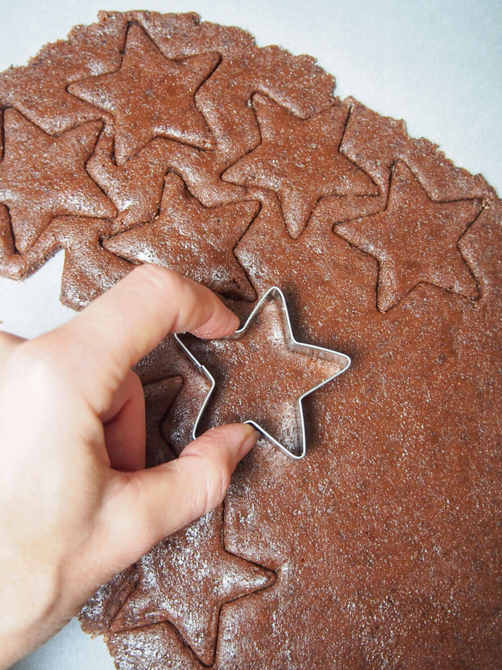 cutting star-shaped chocolate almond cookies from flattened dough