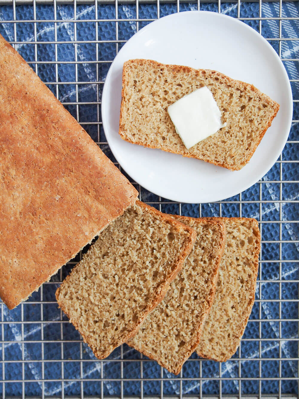 slices of sprouted wheat bread and loaf to side with slice on plate topped with butter