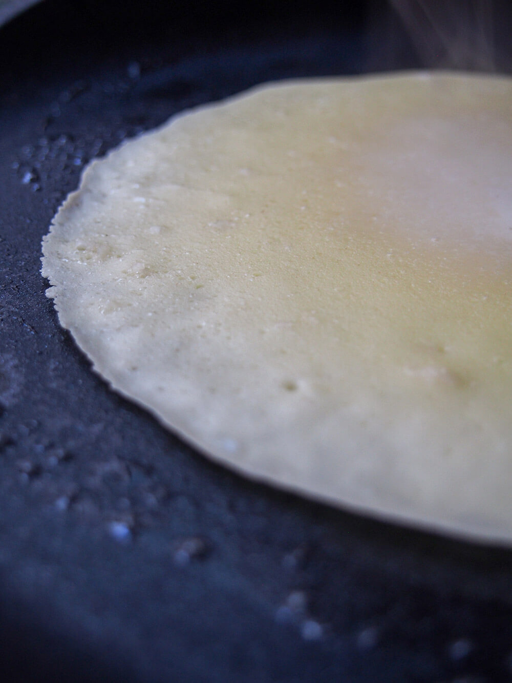 pancake starting to curl at edge as it cooks