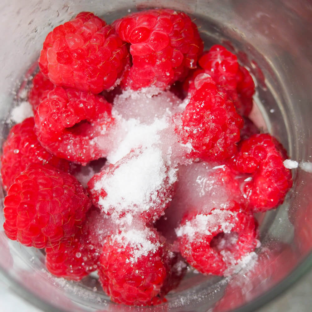 crushing raspberries with sugar