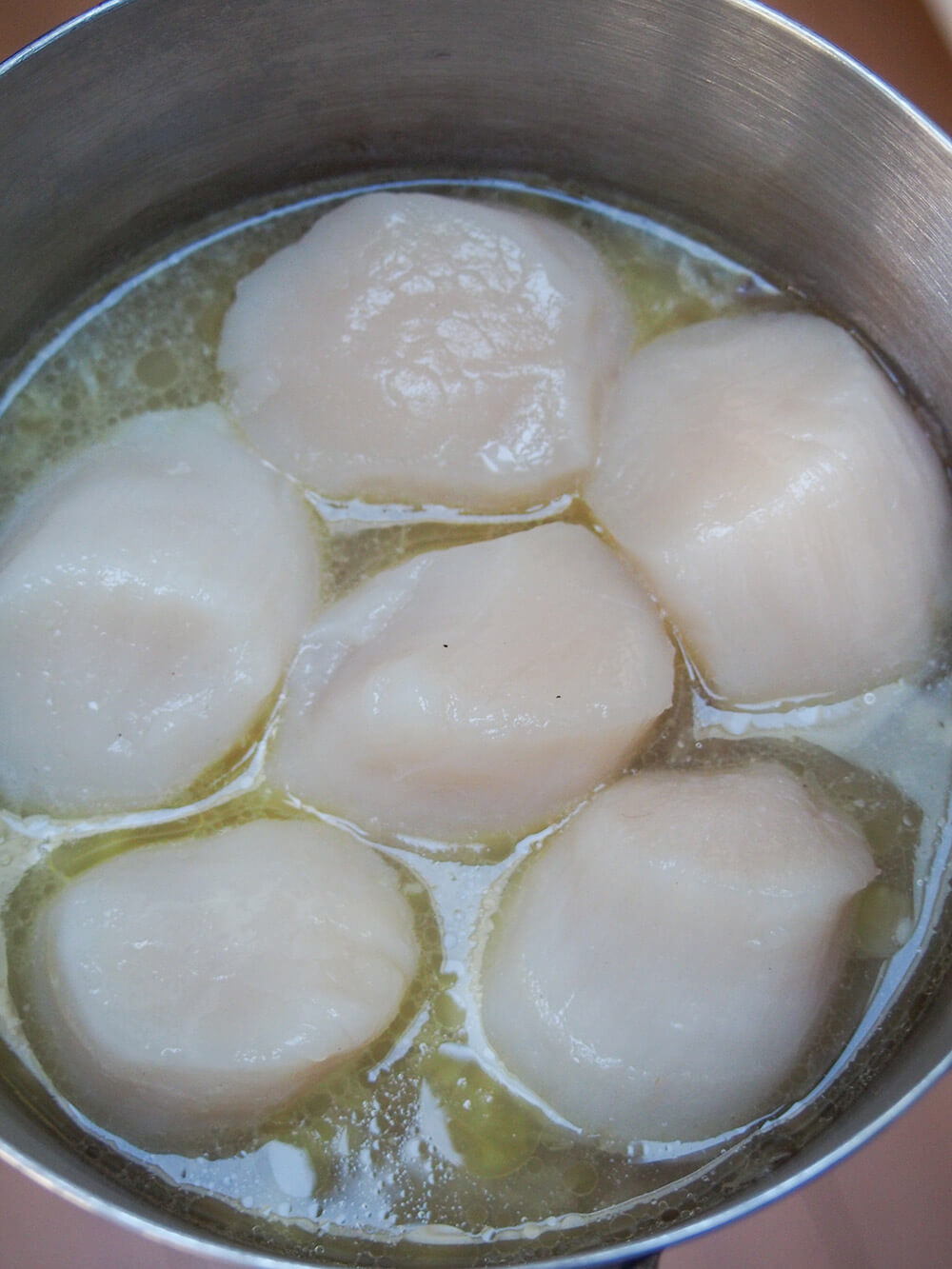 poaching scallops for Coquille St Jacques (scallop gratin) poaching scallops in wine and butter mixture